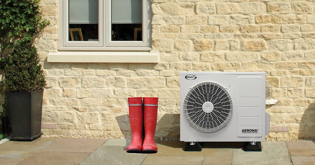 A grant air source heat pump outside a traditional home with red welly boots.